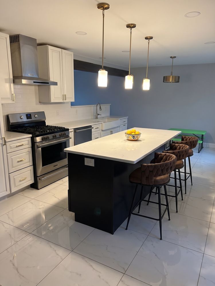 Modern kitchen with white cabinets, black stove, large island, pendant lights, and brown bar stools
