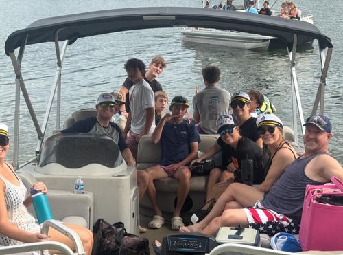 A group of people sitting on a pontoon boat on a sunny day.