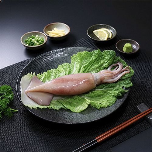 生魷魚放在生菜上，周圍擺放著調味碗和筷子。