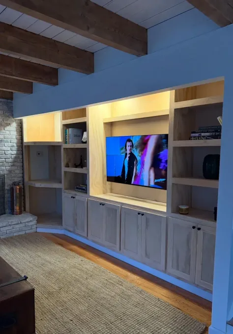 Small white kitchenette with sink, cabinets, fridge, and overhead lights in a plain room