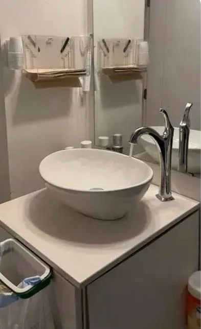 Modern bathroom sink with a white vessel basin, chrome faucet, and wall-mounted hand towels.