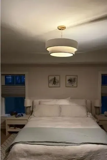 Cozy bedroom with a neatly made bed, soft lamp, and framed art above the headboard
