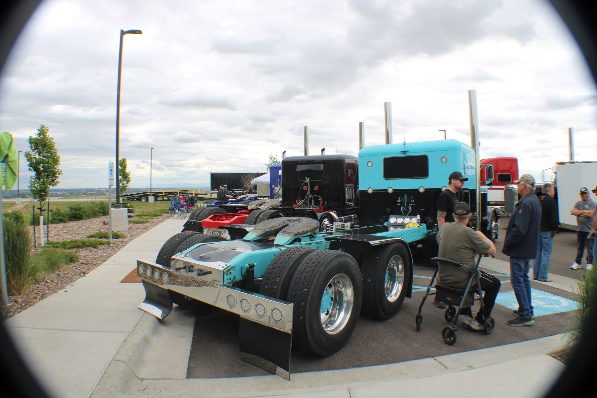 Custom turquoise semi-truck displayed outdoors with people gathered around it