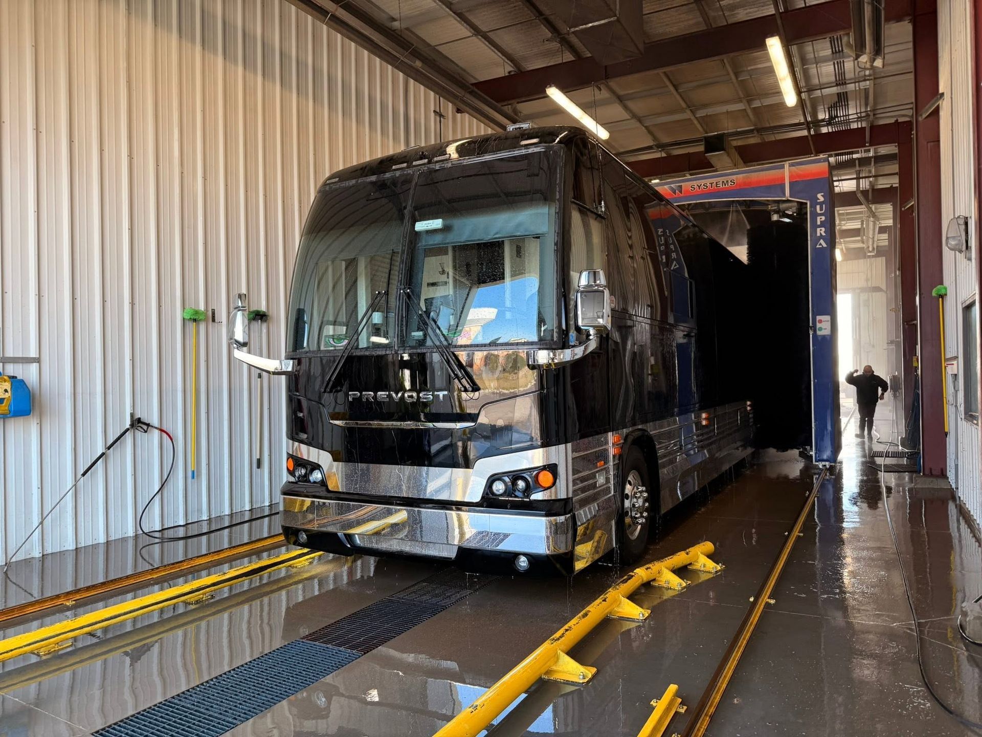 Black coach bus inside a wash bay on a conveyor track