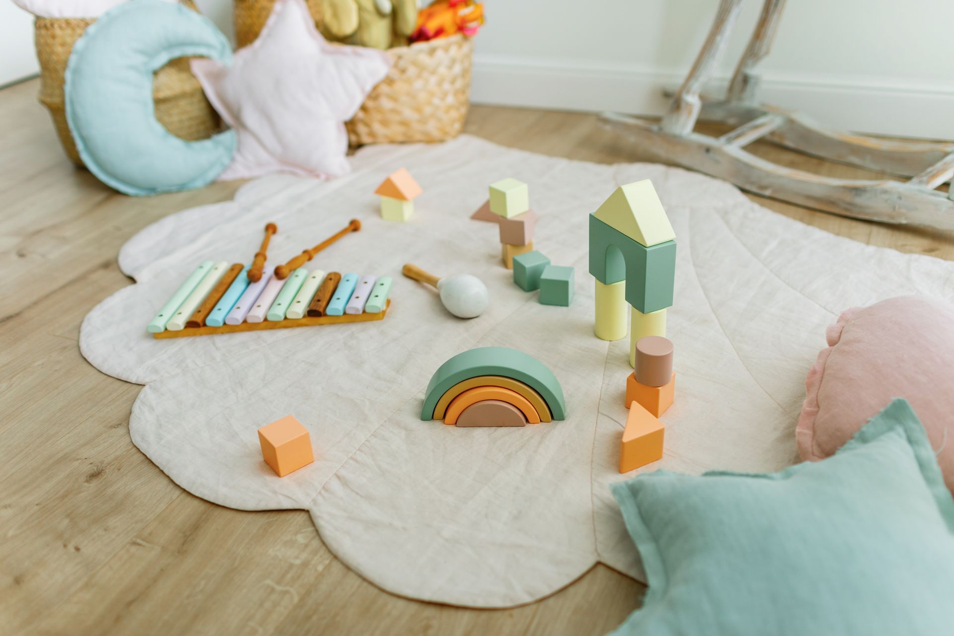 Una stanza per bambini con un tappeto, cuscini, giocattoli e un cavallo a dondolo.