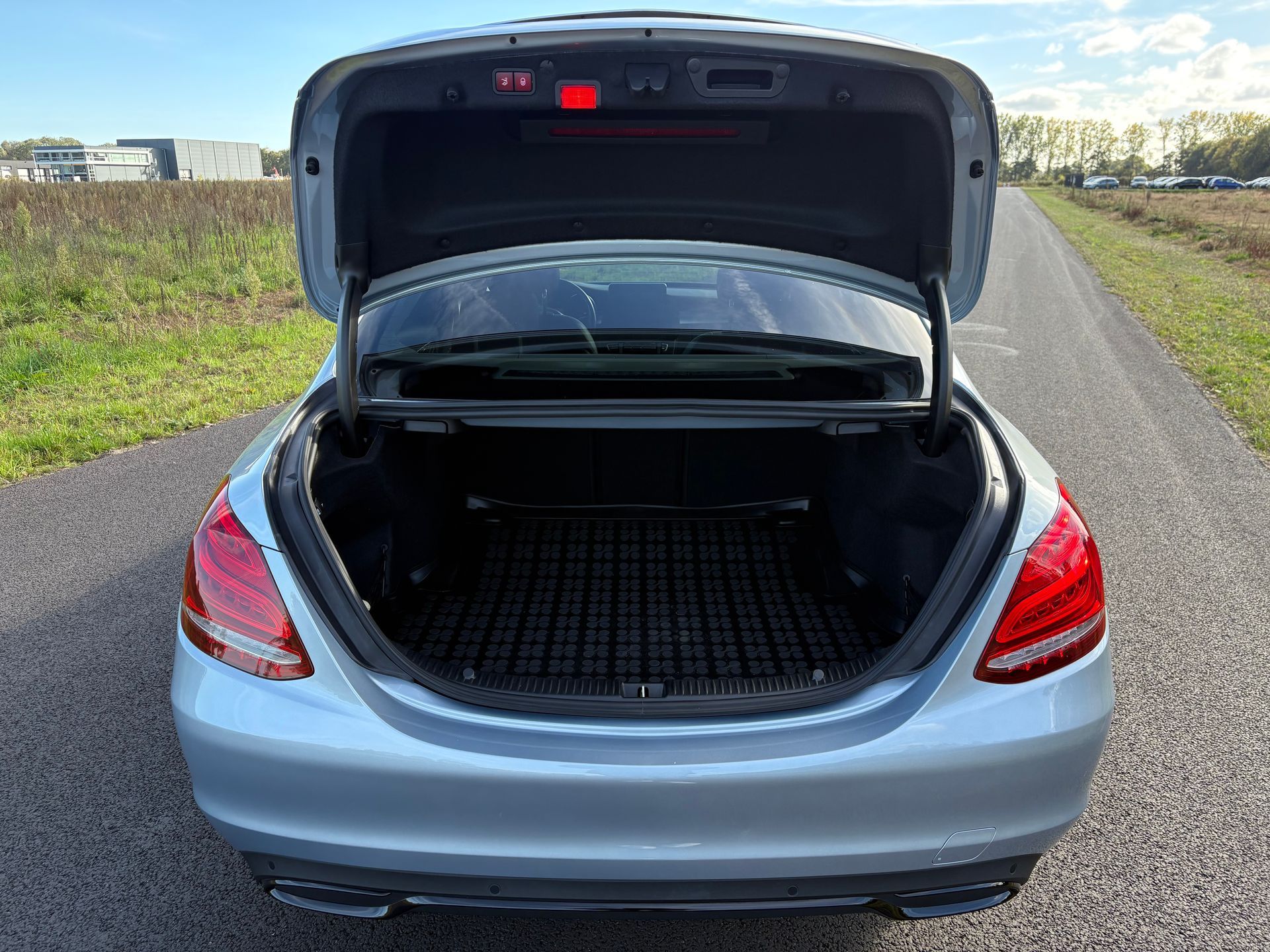 Open kofferbak van een zilverkleurige sedan die langs de weg geparkeerd staat