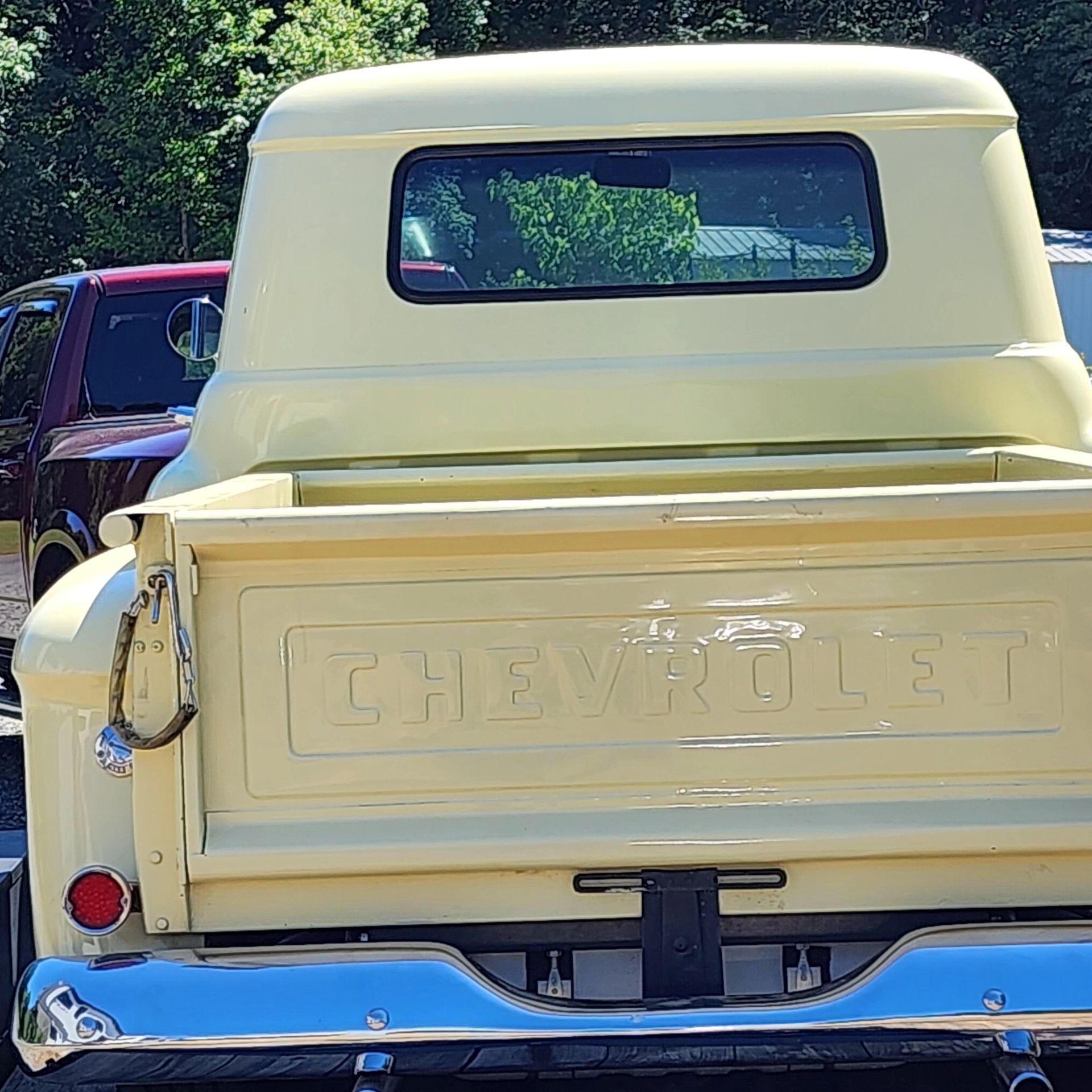 Rear view of a pale yellow Chevrolet pickup with chrome bumper, parked outdoors.
