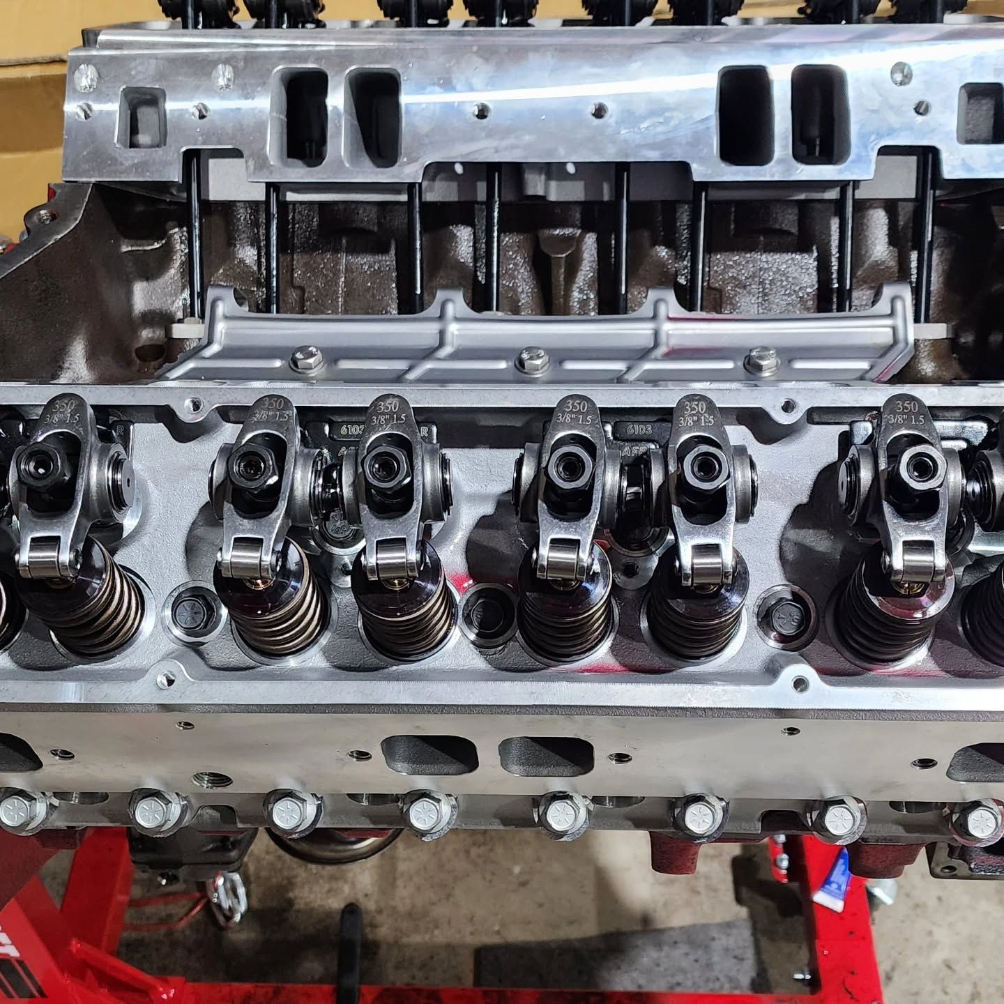 Close-up of a car engine cylinder head with rocker arms and valve springs on a red stand