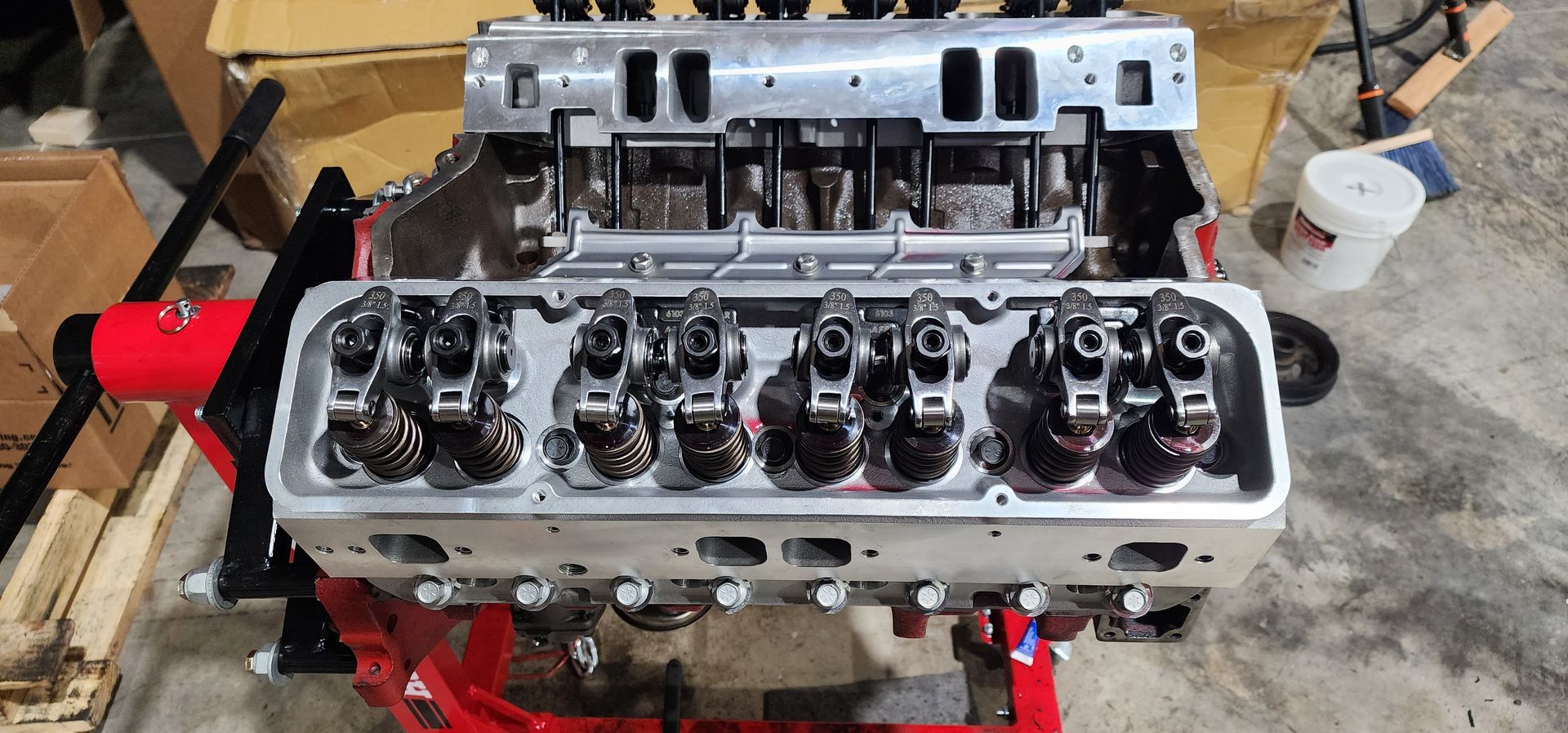 Engine cylinder head on a workbench with exposed valves and red tools in the background