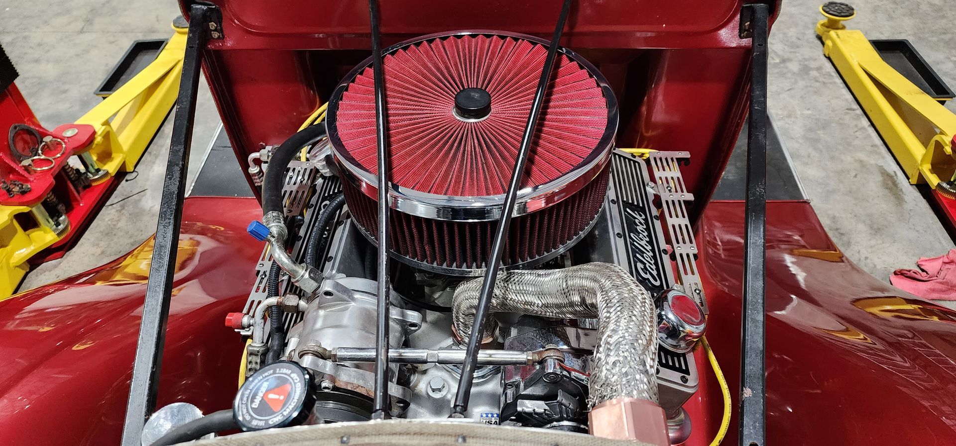 Red engine compartment with circular air filter and visible mechanical parts inside a vehicle