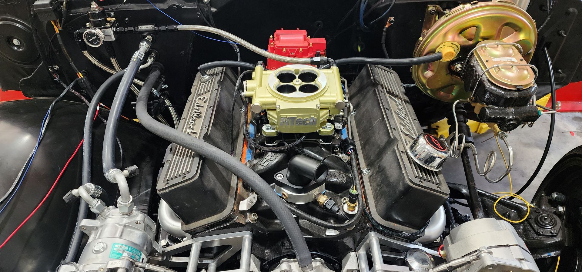 Car engine bay with exposed components, hoses, and a gold brake booster