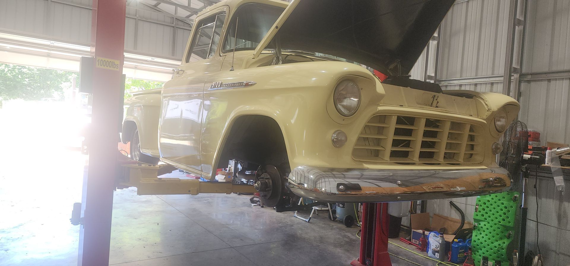 Yellow vintage car body on a lift in a garage, under restoration.