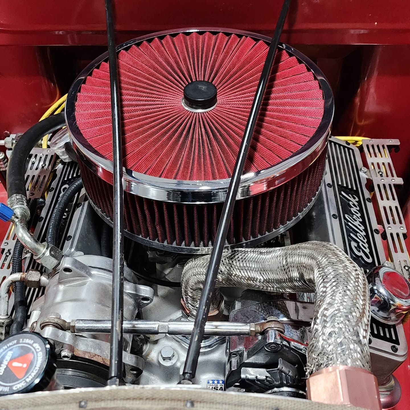 Red engine bay with a large round red air filter and visible hoses and metal components.