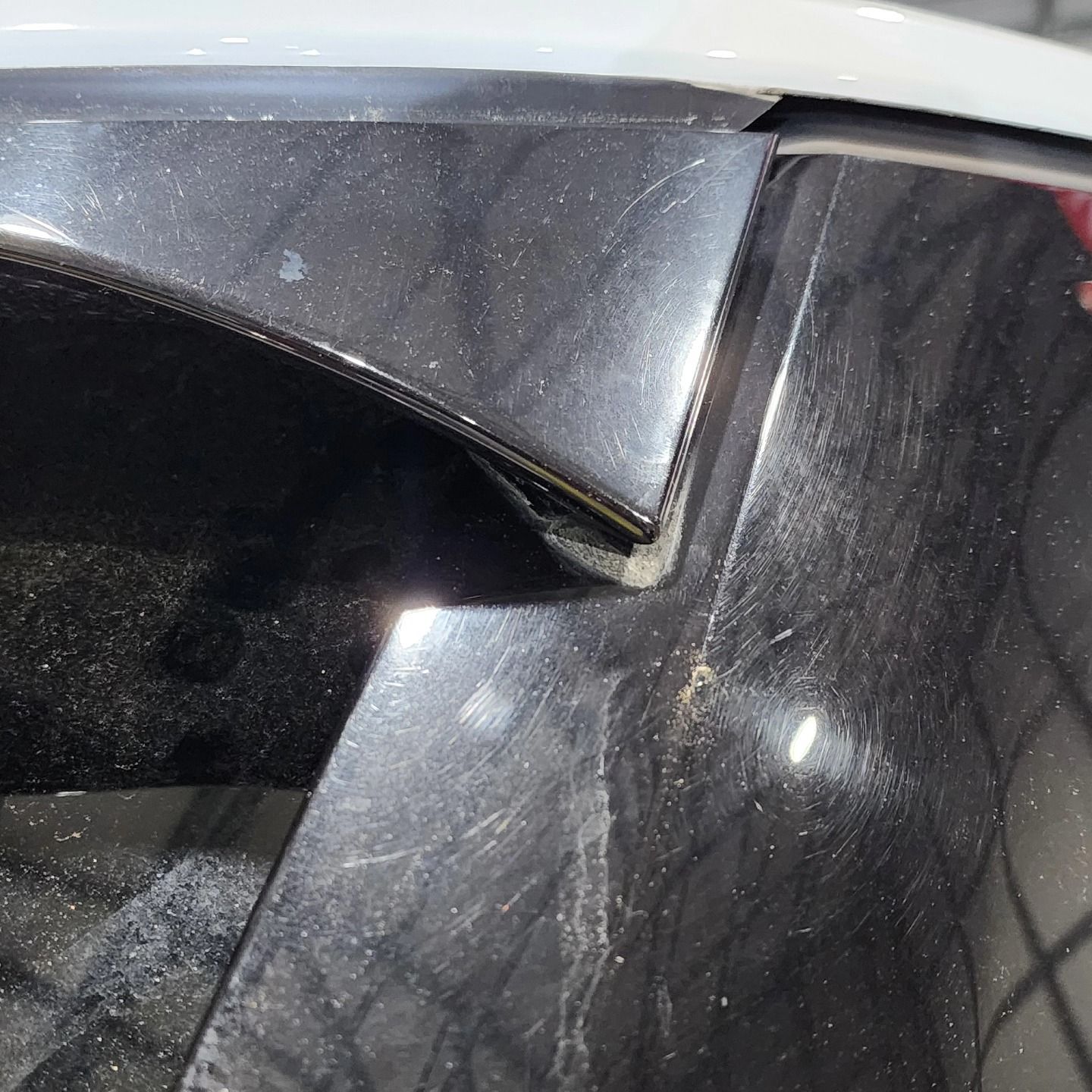 Close-up of a white car’s side window and trim with dusty, scratched glass