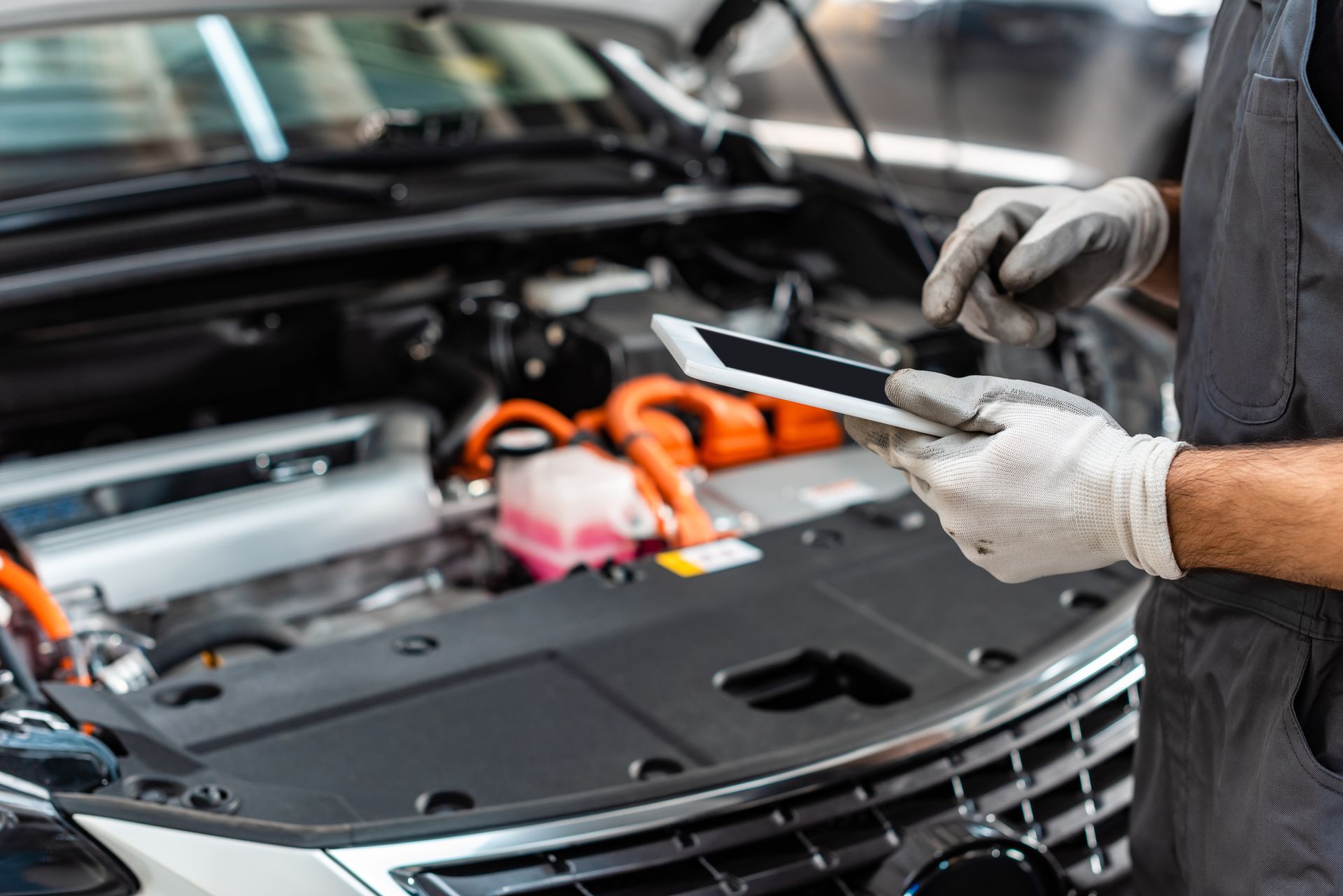 A mechanic is using a tablet computer while working on a car.