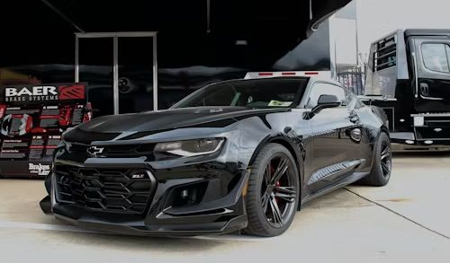 Black Chevrolet Camaro ZL1 sports car parked in front of a trailer.