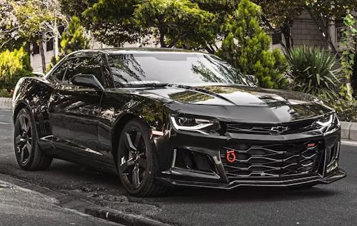 Black Chevrolet Camaro on a road, front view, with black wheels and a red tow hook.