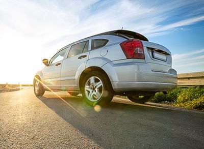 a silver car is parked on the side of a road .