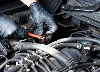 A person is working on a car engine with a wrench.