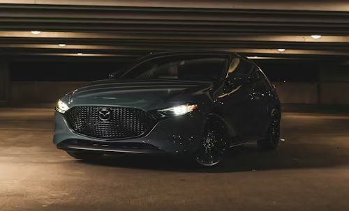 Dark gray Mazda 3 hatchback in a dimly lit parking garage.