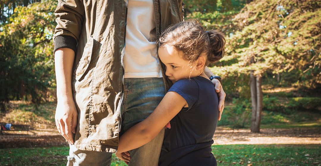 A little girl is hugging a man in a park.