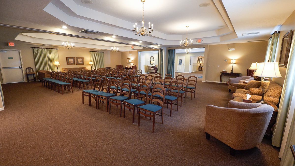 Funeral home chapel with rows of chairs facing an altar, plus sofas and lamps.