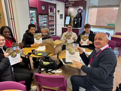 A group of people are sitting around a table holding flyers.