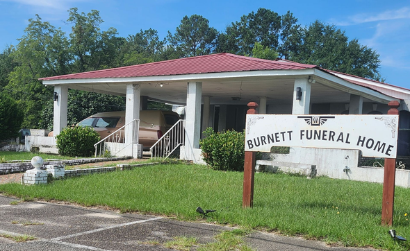 Burnett Funeral Home building with red roof and front sign on a sunny day