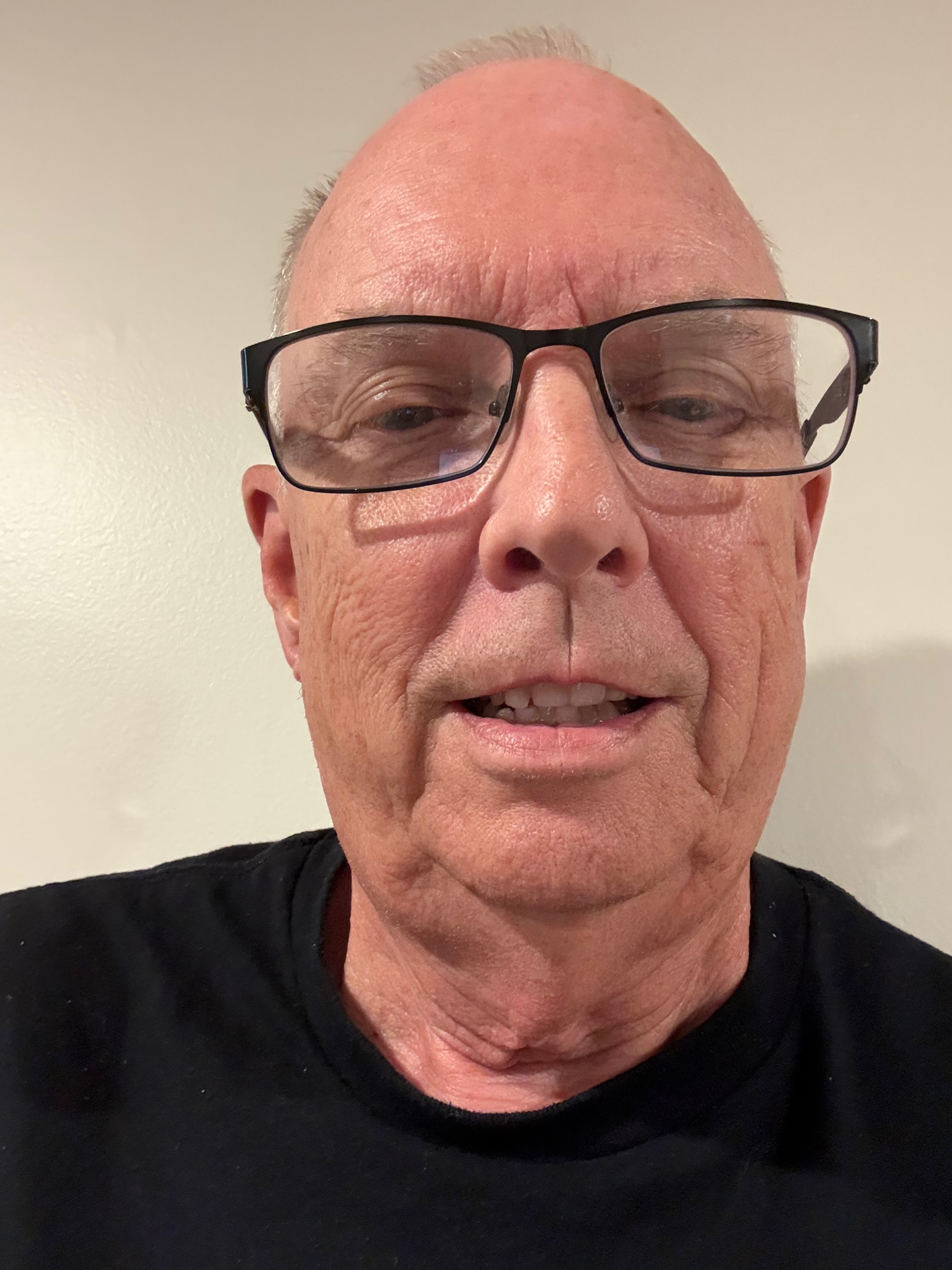 Man with glasses smiling, wearing a black shirt