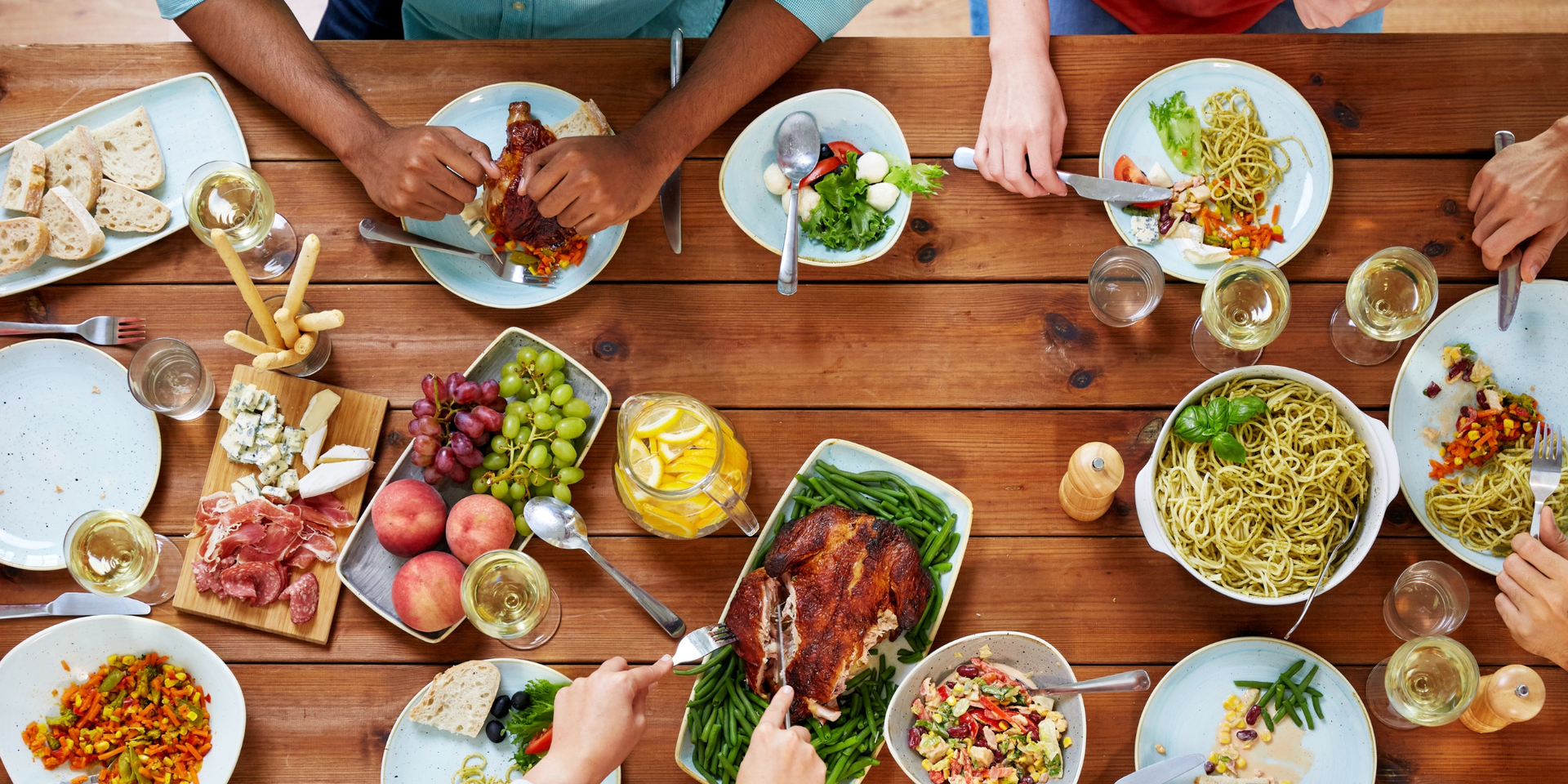 People gathered at a buffet table with food, balloons, and a large window in the background.