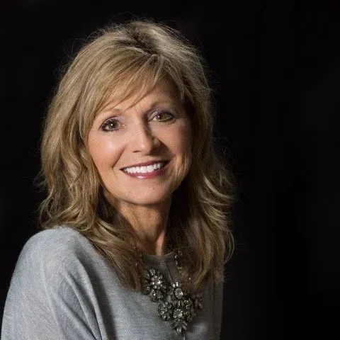 woman in grey shirt smiling at camera