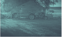 Old wooden barn with tractor in a field, bathed in a blue-green light.