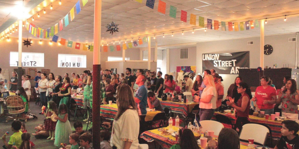 People gathered in a room decorated with colorful flags and lights.