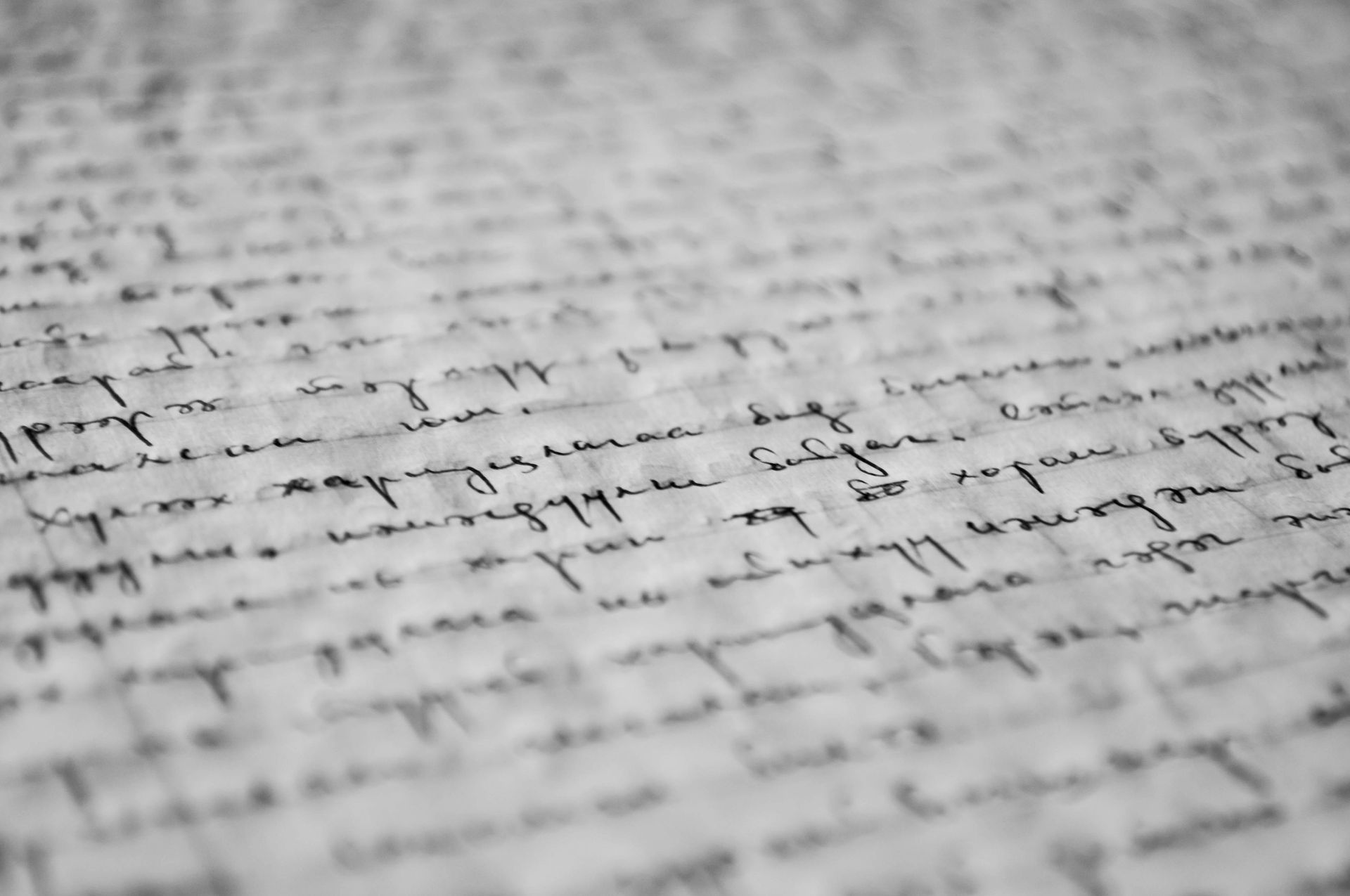 Close-up of a handwritten document in a cursive script, blurred with aged paper background.