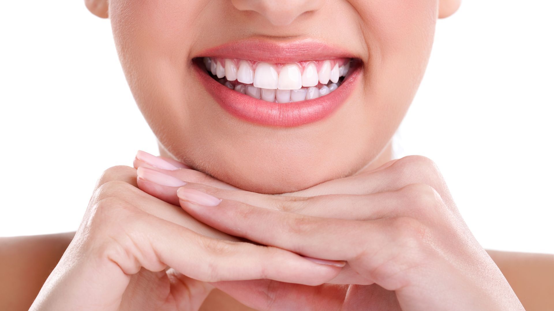 Un primo piano del sorriso di una donna con le mani sul mento.