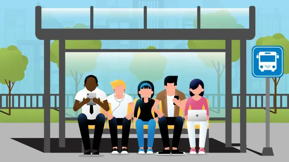 A group of people are sitting at a bus stop.