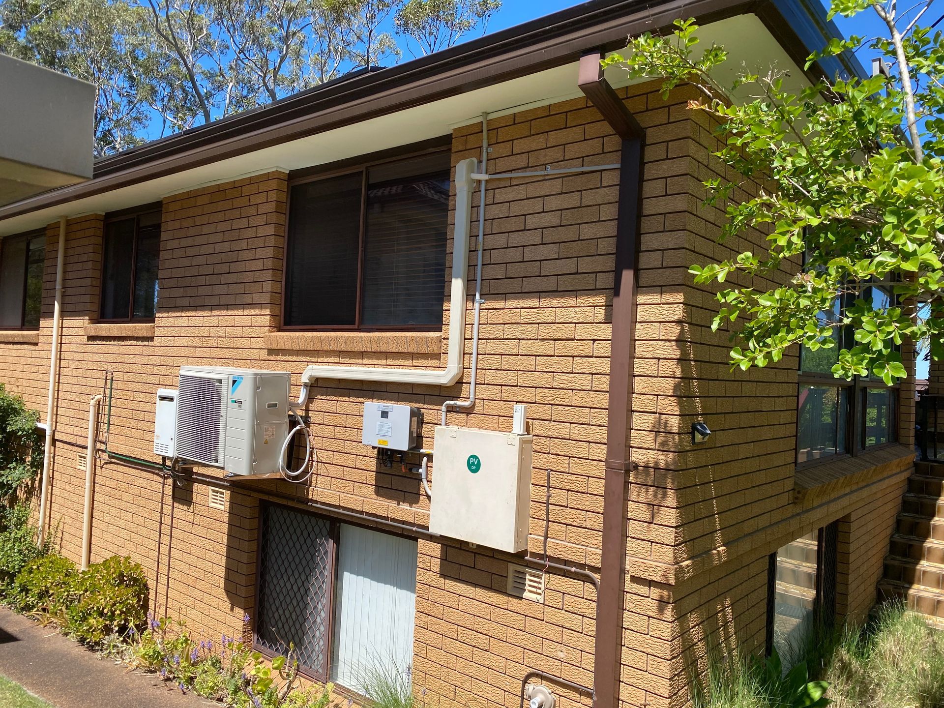 Brick building with brown gutters, windows, and air conditioning units. — Airweld Services Pty Ltd in Shellharbour, NSW