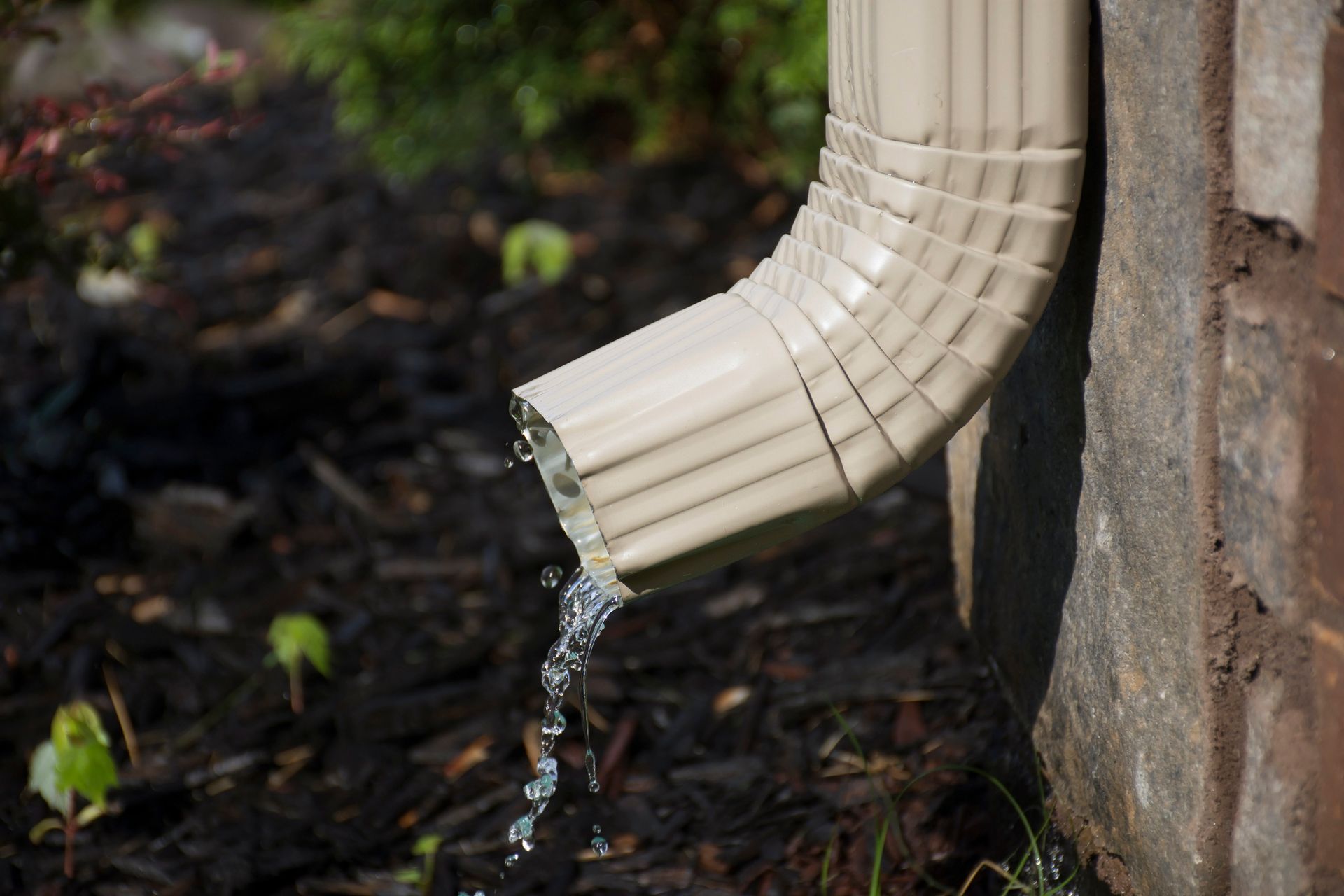 A close up of a gutter with water coming out of it.