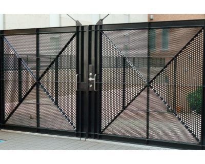 A black metal gate with a brick wall behind it