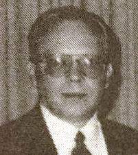 Man wearing glasses and a suit, looking forward.