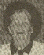 Woman wearing glasses, dark hair, and a collared jacket, in a grayscale portrait.