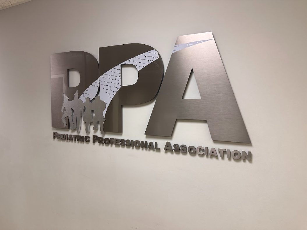 A sign for the pediatric professional association hangs on a wall