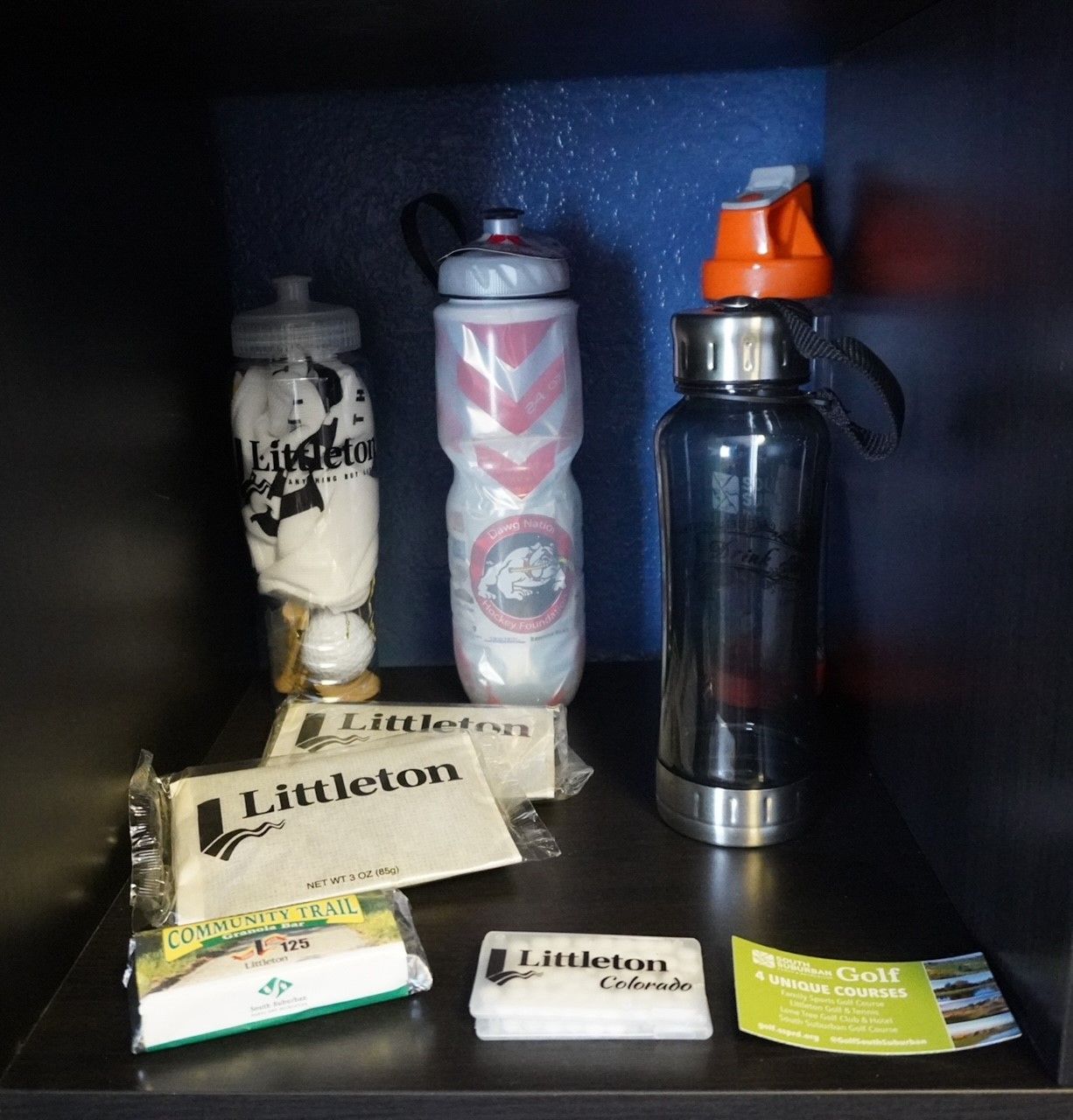 Shelf with three water bottles, tissue packets, and brochures.