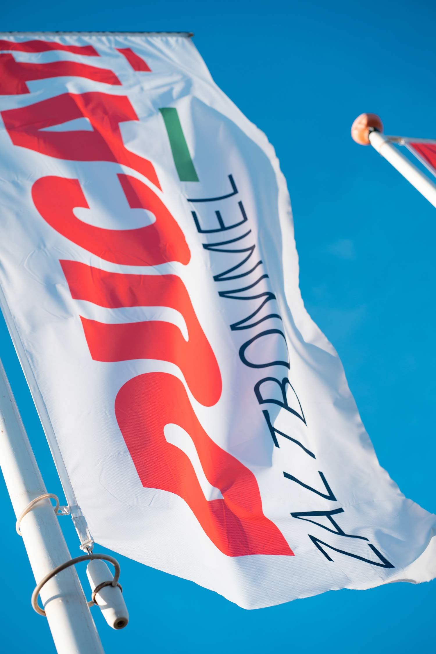 Flag with red lettering on white, against a blue sky.