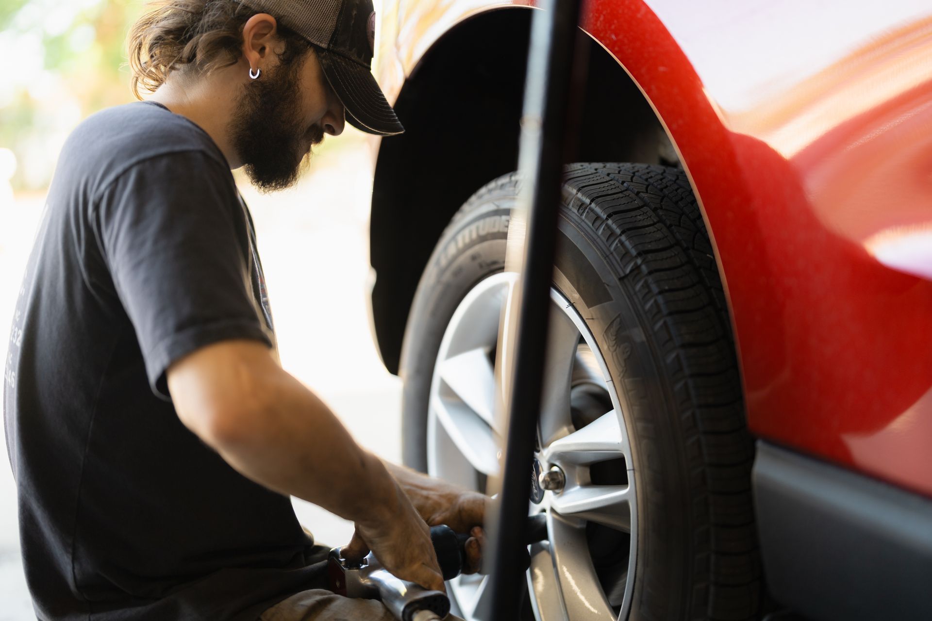 Mechanic working on a red car’s front wheel in a garage
