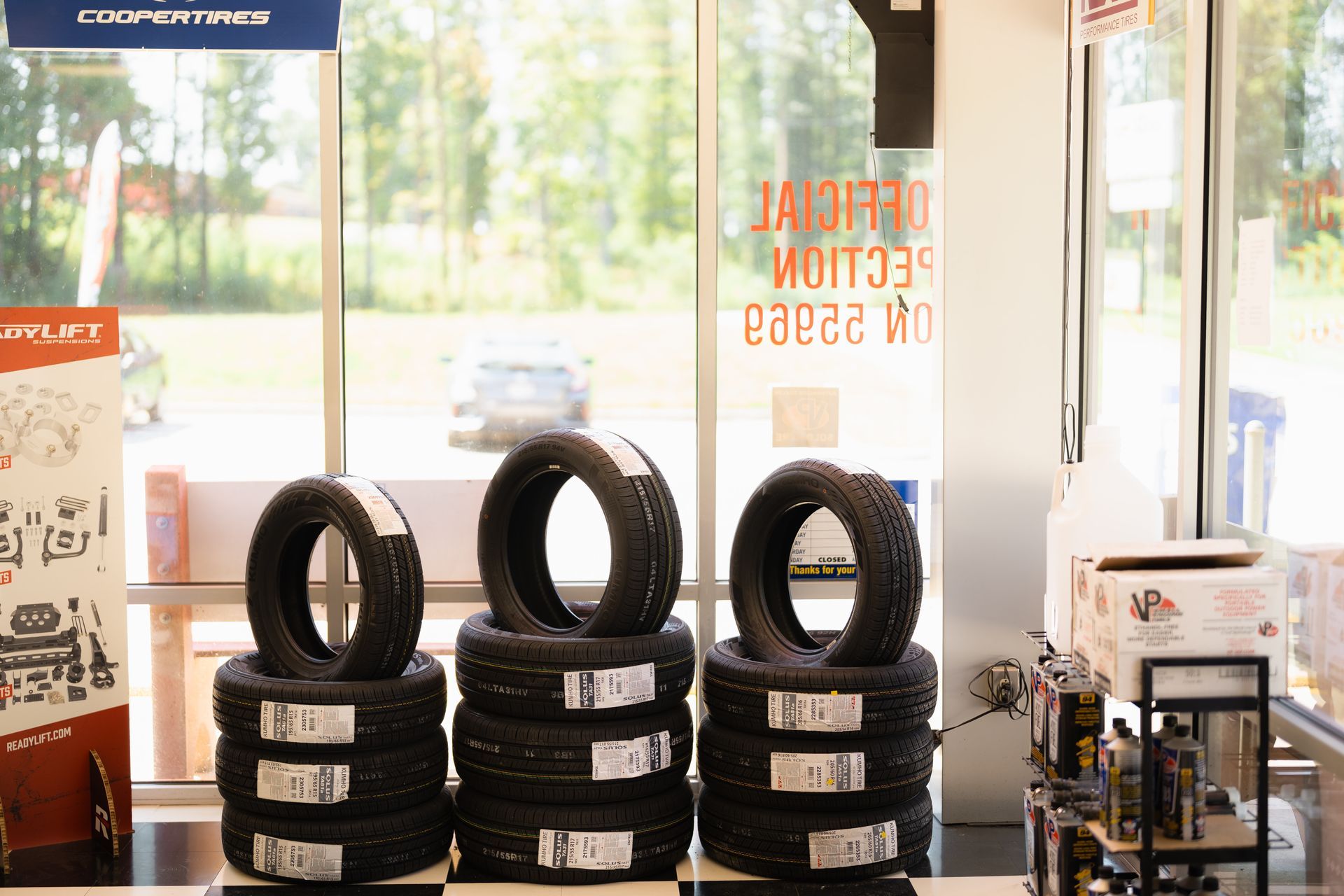 Tire shop display with stacked black tires and a bright storefront window behind them