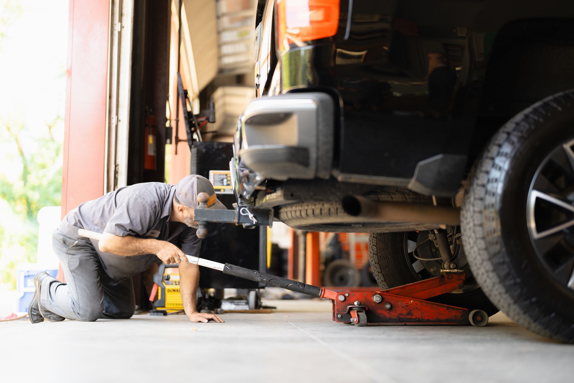 Mechanic repairing a car with a floor jack in a garage