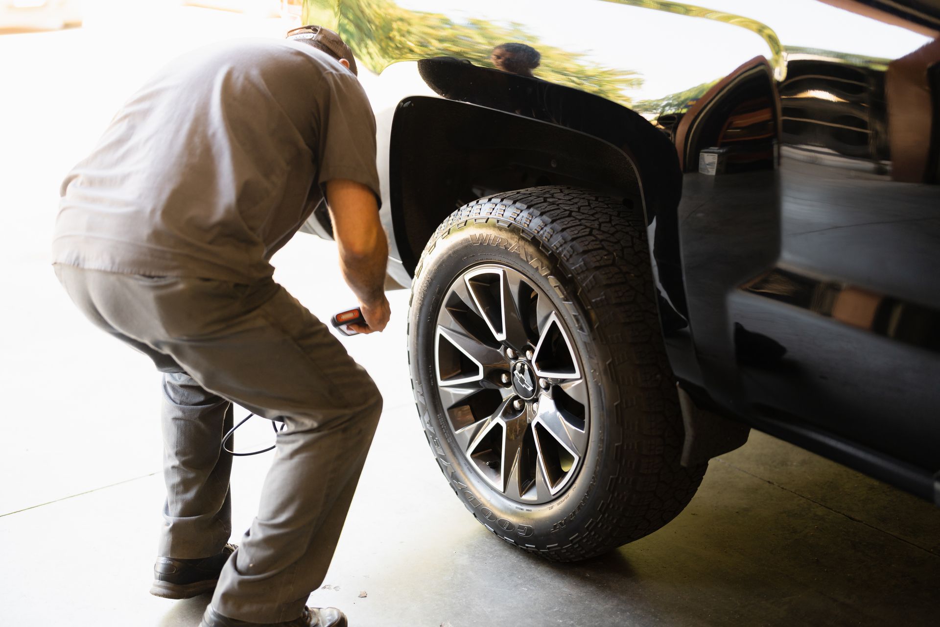 Mechanic inspecting a black pickup truck’s rear wheel in a garage