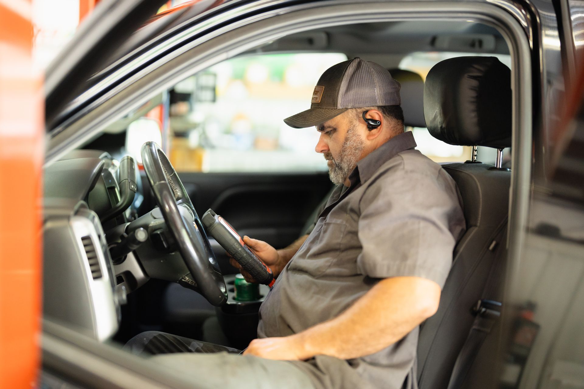 Driver seated in a car, looking at a smartphone while holding the steering wheel