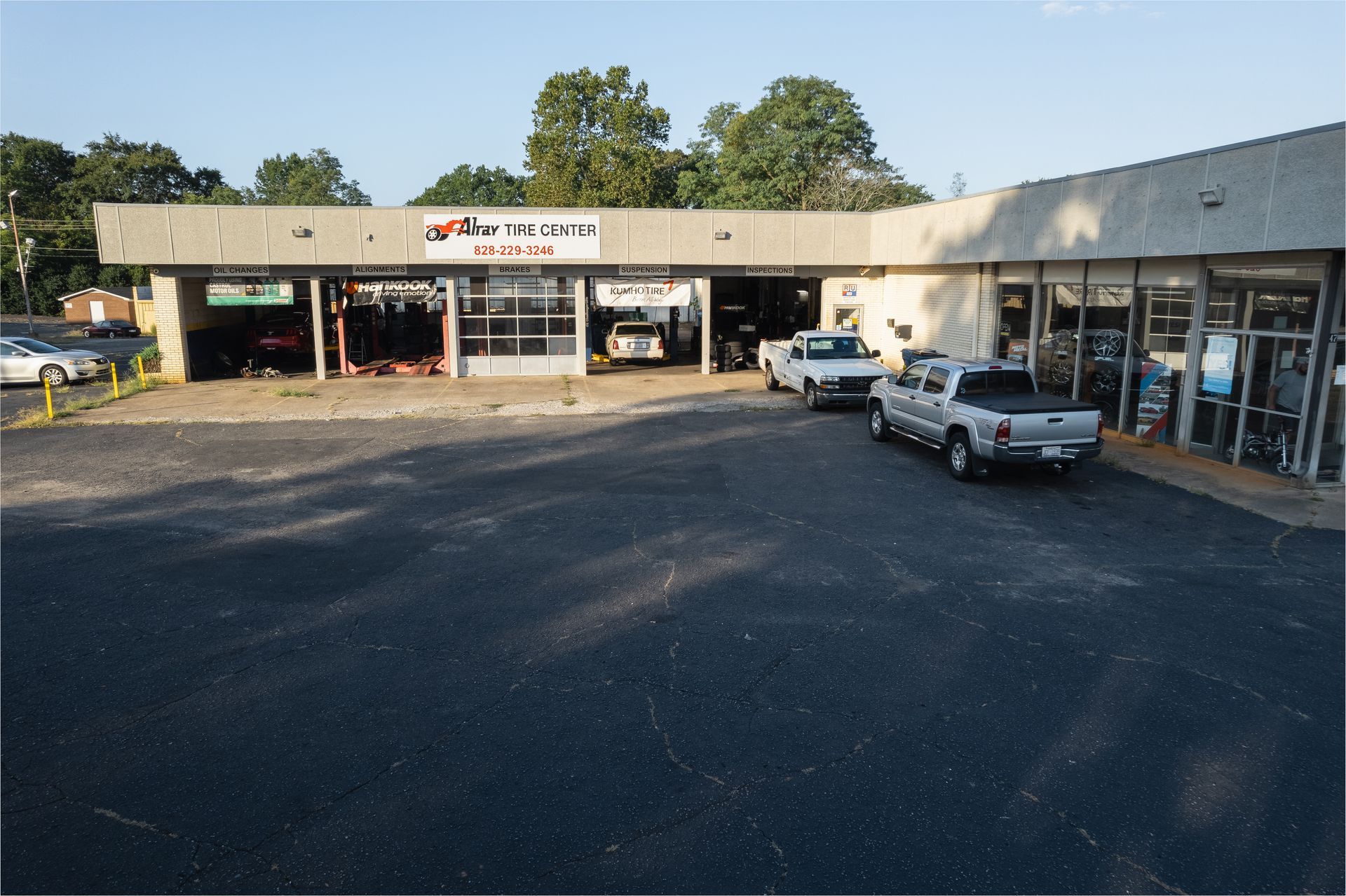 Small auto repair shop strip mall with parked pickup trucks and open service bays